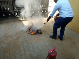 消火器を使って火を消す方法を模擬演習するインストラクター